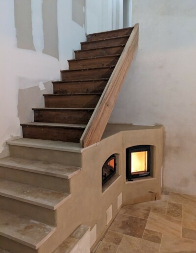 Poêle de masse escalier, marche en travertin et enduit chaux aérienne